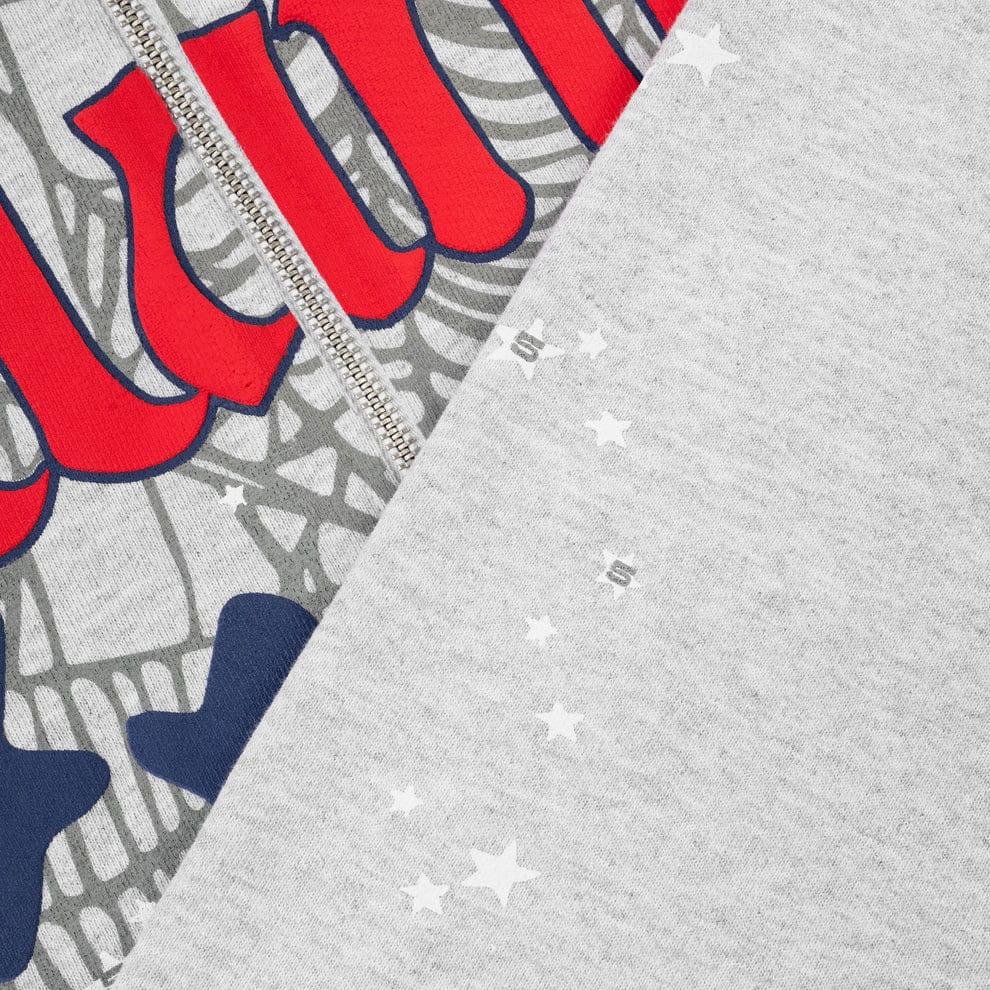 Close-up of the Sp5der Atlanta Web Zip Hoodie – Grey 440GSM Heavyweight Streetwear, showing part of its graphic with red and blue text, white stars, and a visible zipper seam.