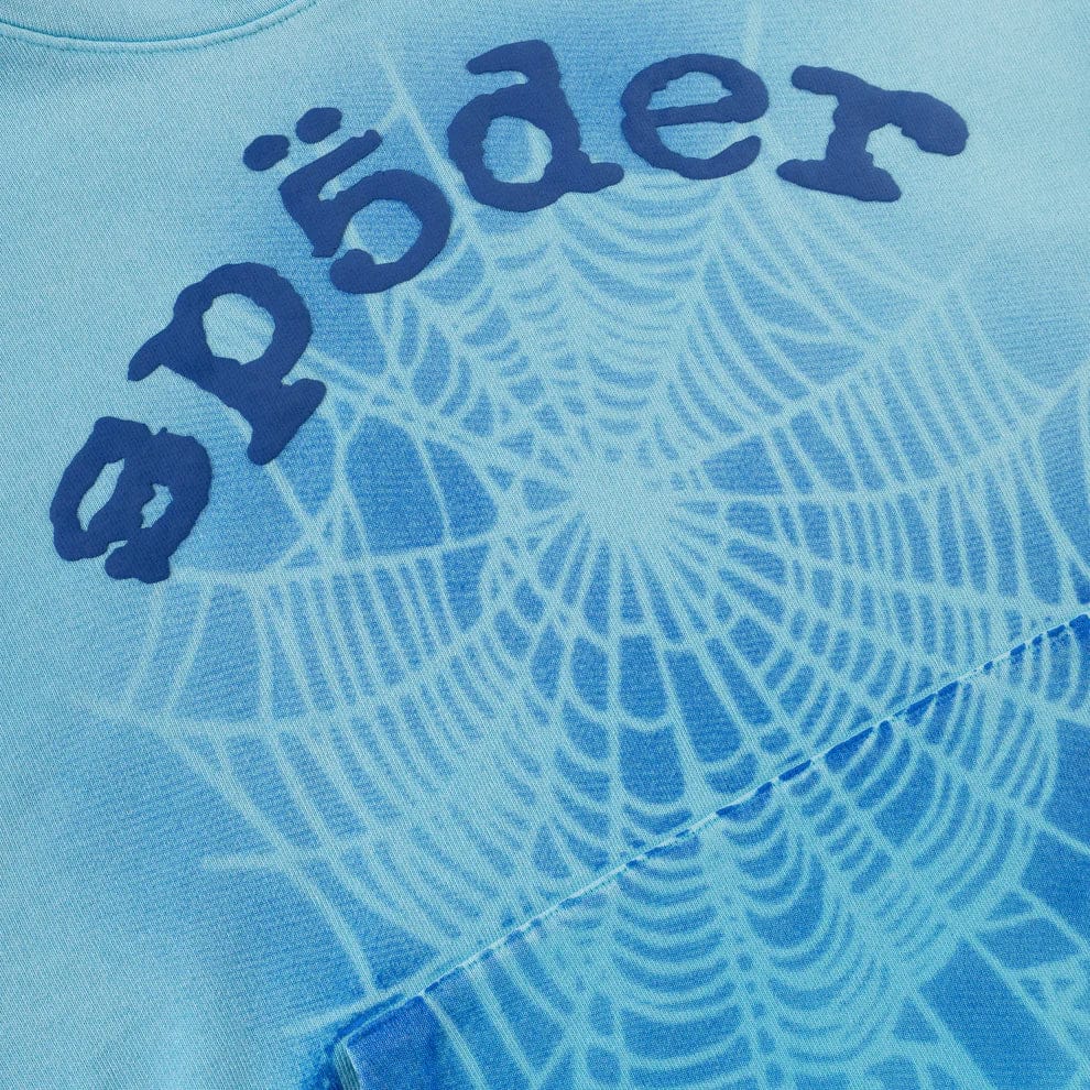 The Sp5der “Blue Venom” Web Hoodie features a sky blue fade and printed web design with stylized Sp5der text, crafted from 440GSM heavyweight cotton fleece for an oversized streetwear look.