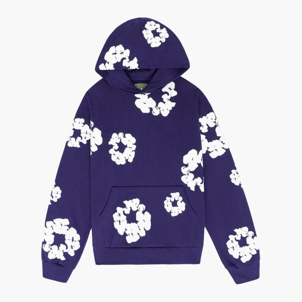 The Purple “Cotton Wreath” Denim Tears Hoodie features bold white floral prints scattered on a purple pullover, inspired by the iconic cotton wreath motif and classic streetwear style.