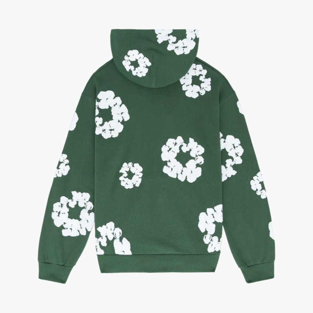 The Forest Green “Cotton Wreath” Denim Tears Hoodie is a streetwear pullover with white abstract floral prints inspired by the Cotton Wreath motif, scattered on the back, hood, and sleeves—a signature Denim Tears design.