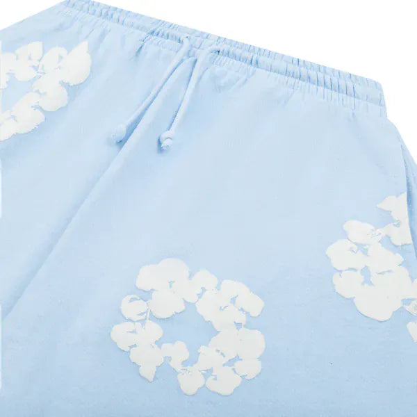 Light Blue “Cotton Wreath” Denim Tears Sweatpants feature a white floral print and adjustable drawstring waistband, blending streetwear style with signature Denim Tears design.