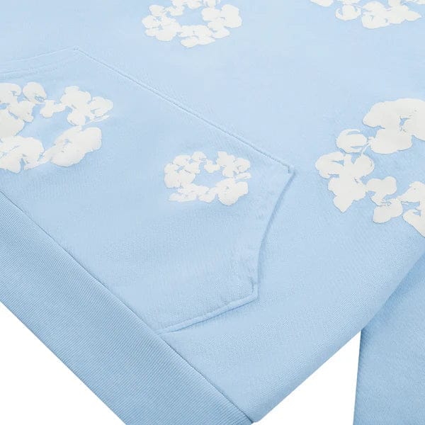 Light Blue “Cotton Wreath” Denim Tears Hoodie – a soft streetwear pullover with a sewn pocket and scattered white floral print, featuring subtle cotton wreath-inspired details.