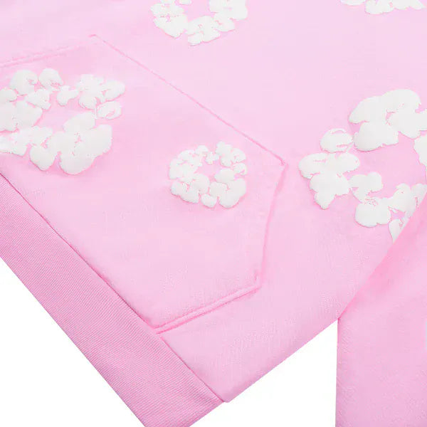 Close-up of the Pink “Cotton Wreath” Denim Tears Hoodie—a soft cotton streetwear pullover with a front pocket and white floral print scattered across its light pink fabric.