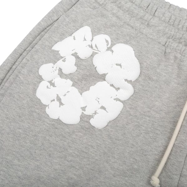 Close-up of Grey “Cotton Wreath” Denim Tears Sweatpants, featuring a white floral print and drawstring waistband—stylish streetwear pants.