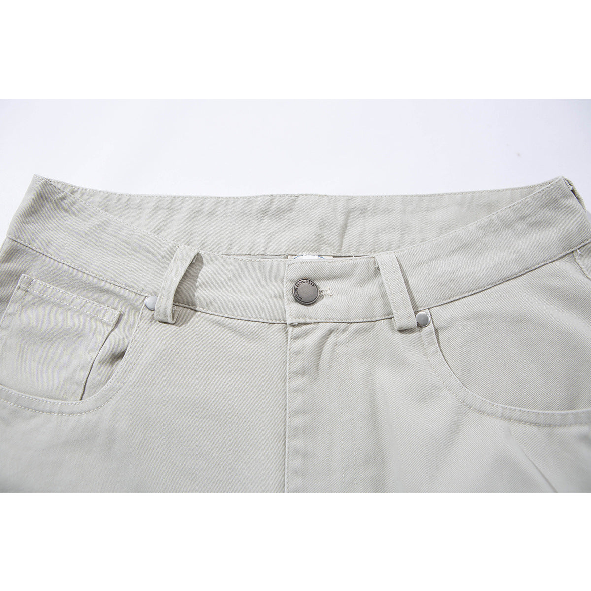 Close-up of light gray shorts showing the waistband, button, belt loops, fly seam, and front pockets.