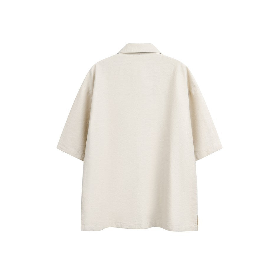 Back view of a beige short-sleeve shirt with a folded collar and small side slits at the hem