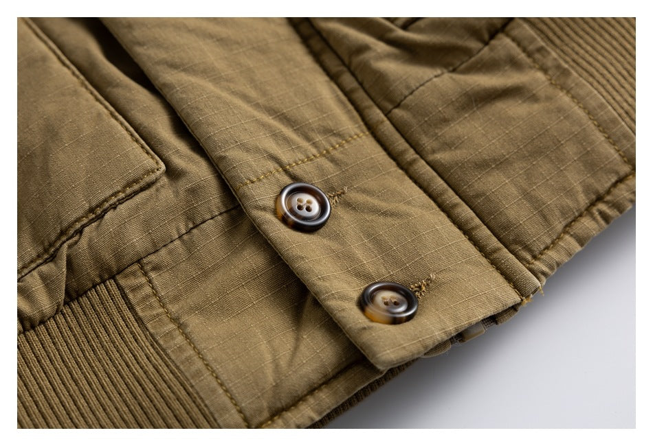 Close-up of two brown buttons, stitching, and a ribbed hem on an olive-brown jacket.