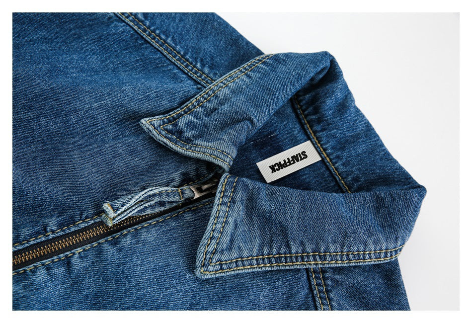 Close-up of the blue denim jacket's collar, zipper, stitching, and a small sewn-in label.