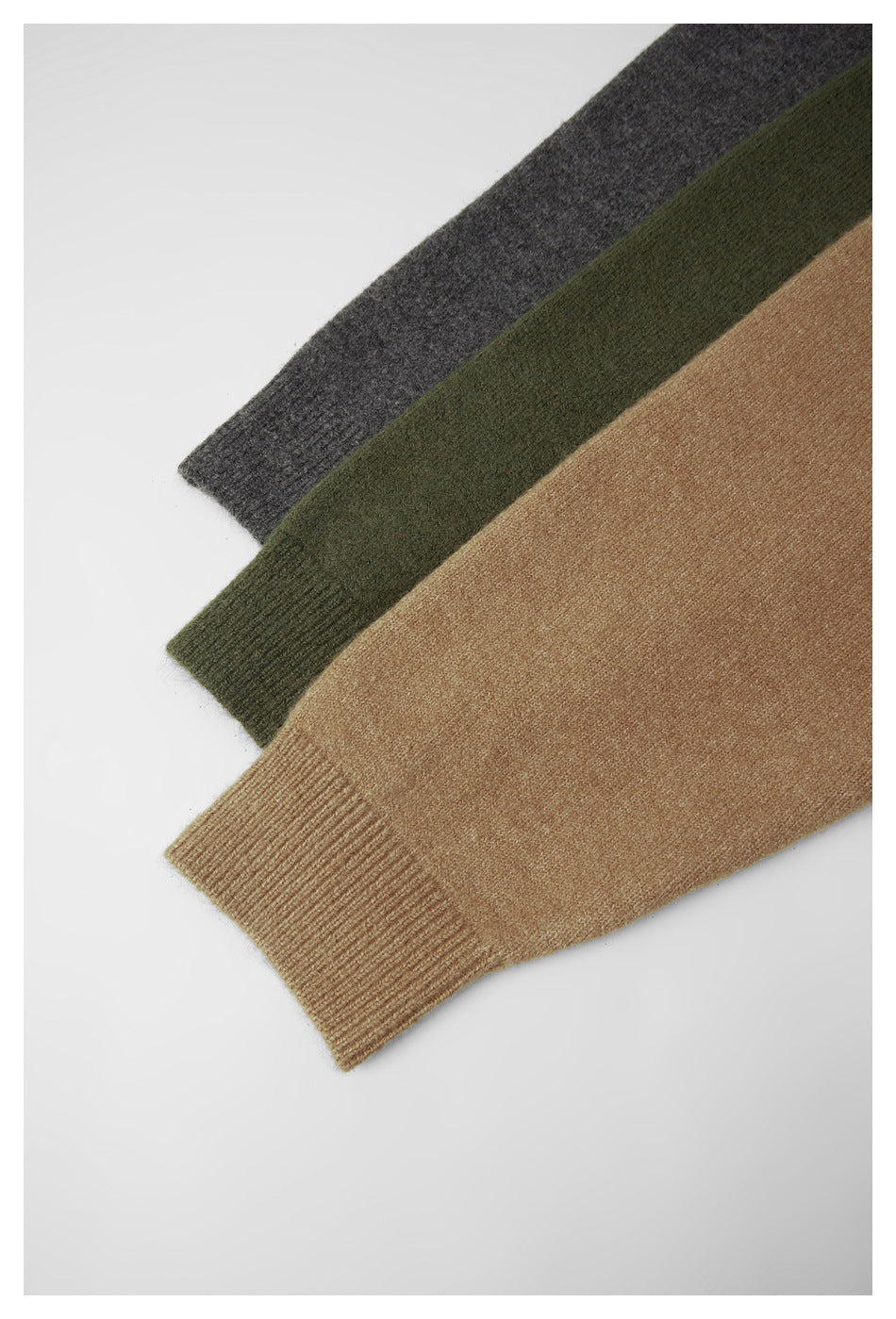 Cropped view of three knit sleeves in charcoal gray, olive green, and camel, showing ribbed cuffs.