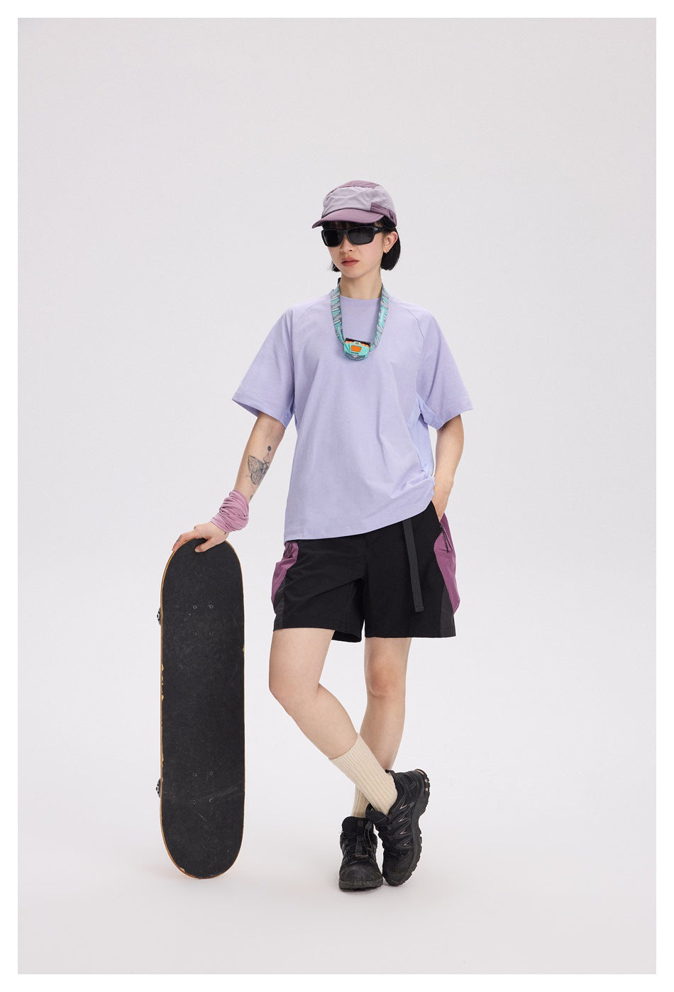 A woman models a loose lavender short-sleeve T-shirt and black shorts with mauve side panels.