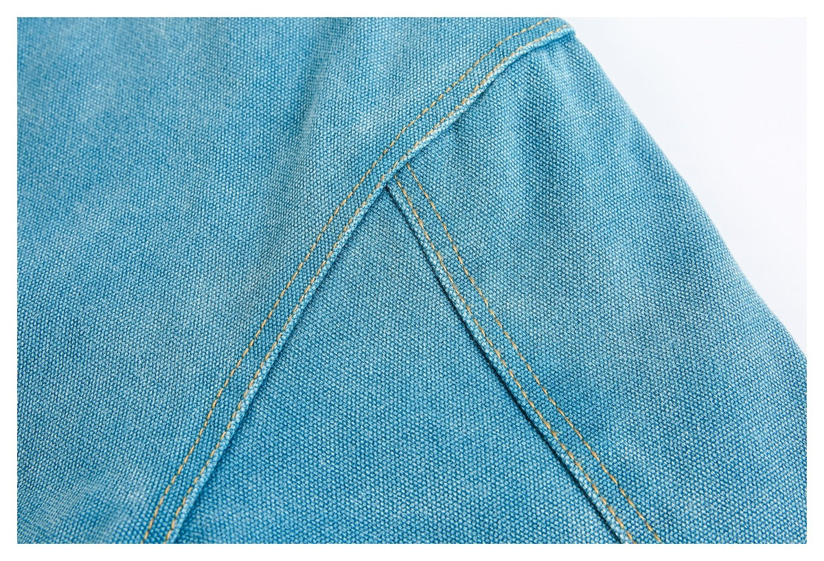Close-up of blue woven garment panels joined by a diagonal seam with double ochre stitching.