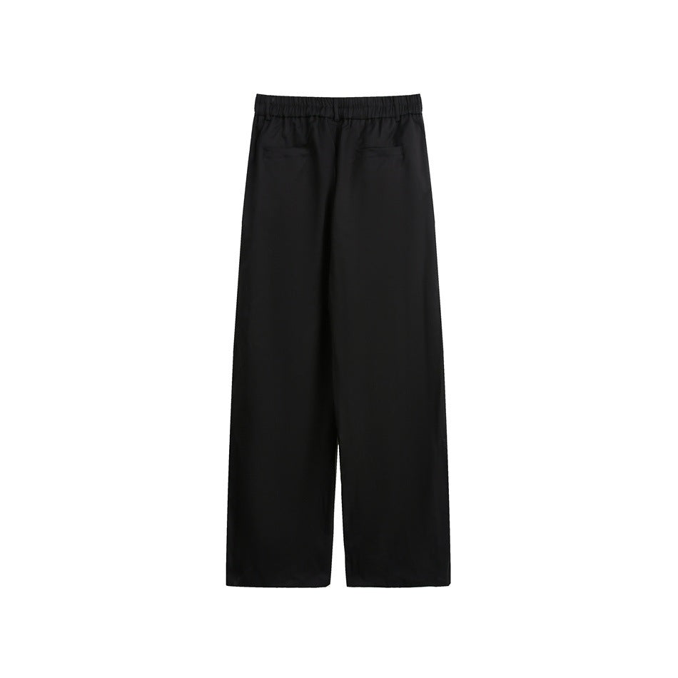 Black wide-leg trousers shown from the back, with an elastic waistband and two welt pockets.