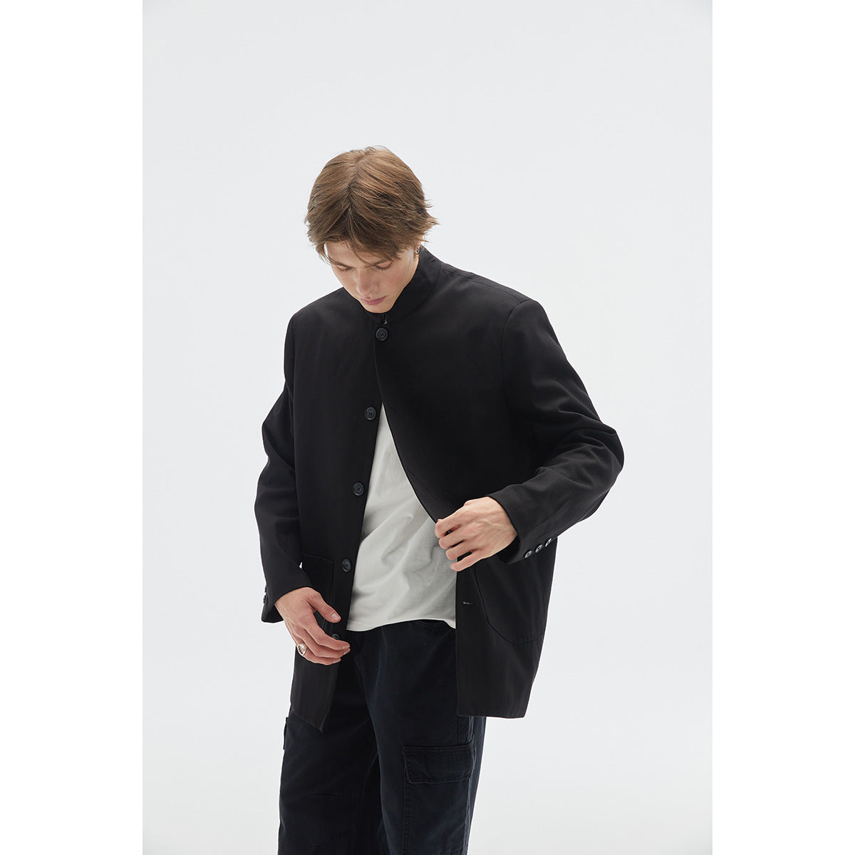 Model in a black stand-collar button-front jacket, shown from the waist up with the jacket partly open.