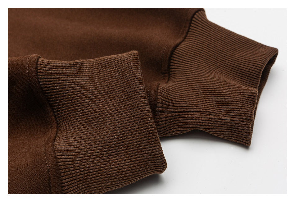 Close-up of brown sweatshirt sleeves showing wide ribbed cuffs and stitching.