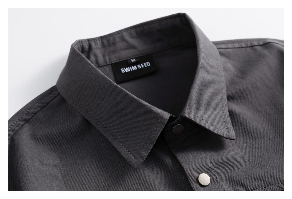 Close-up of a charcoal shirt collar, neck label, and metal snap buttons.