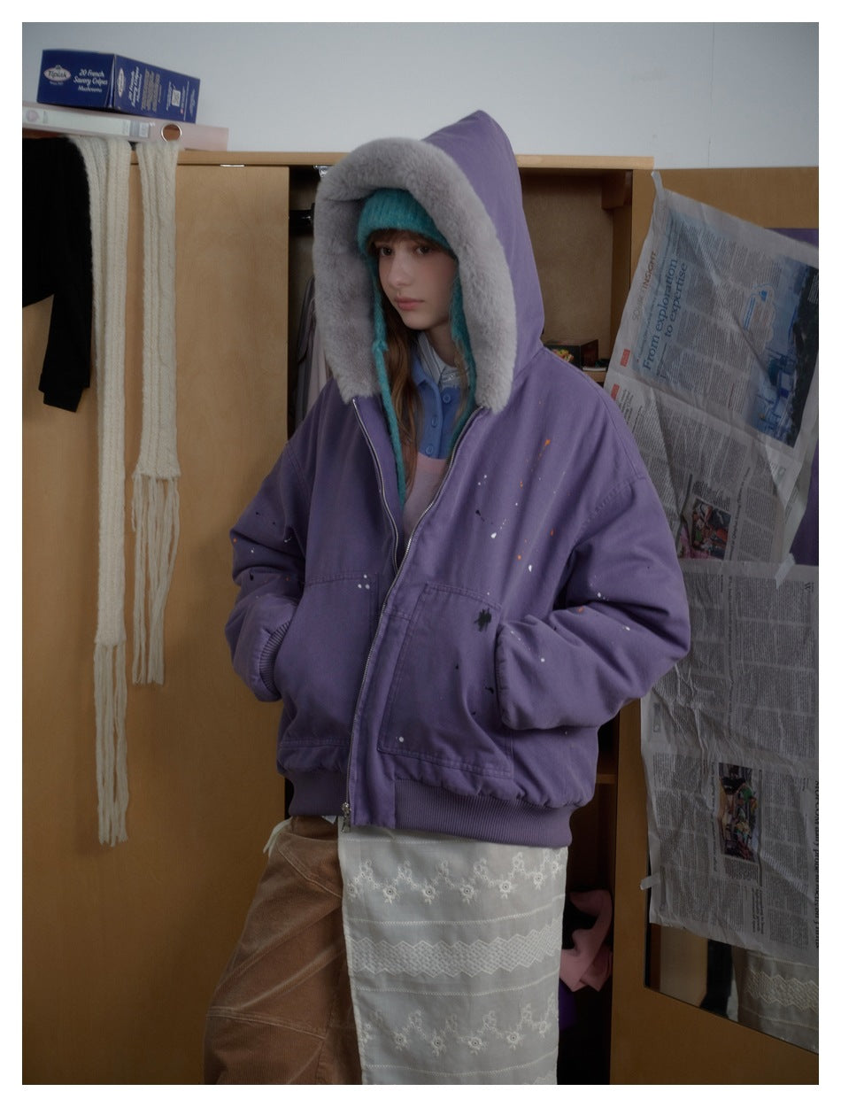 Three-quarter view of a model wearing a purple hooded jacket with a wide gray plush lining.