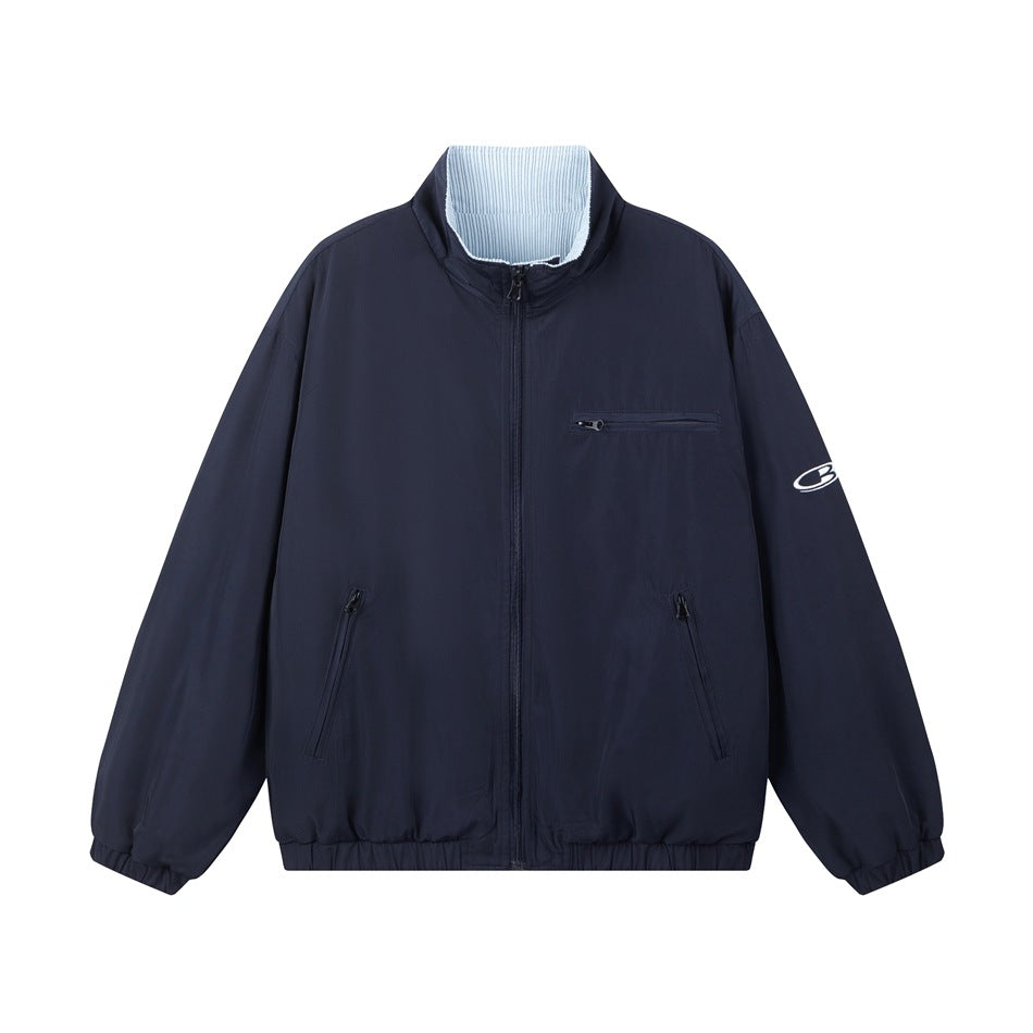Navy zip-up stand-collar jacket flat lay with zippered pockets, elastic hem and light blue striped inner collar
