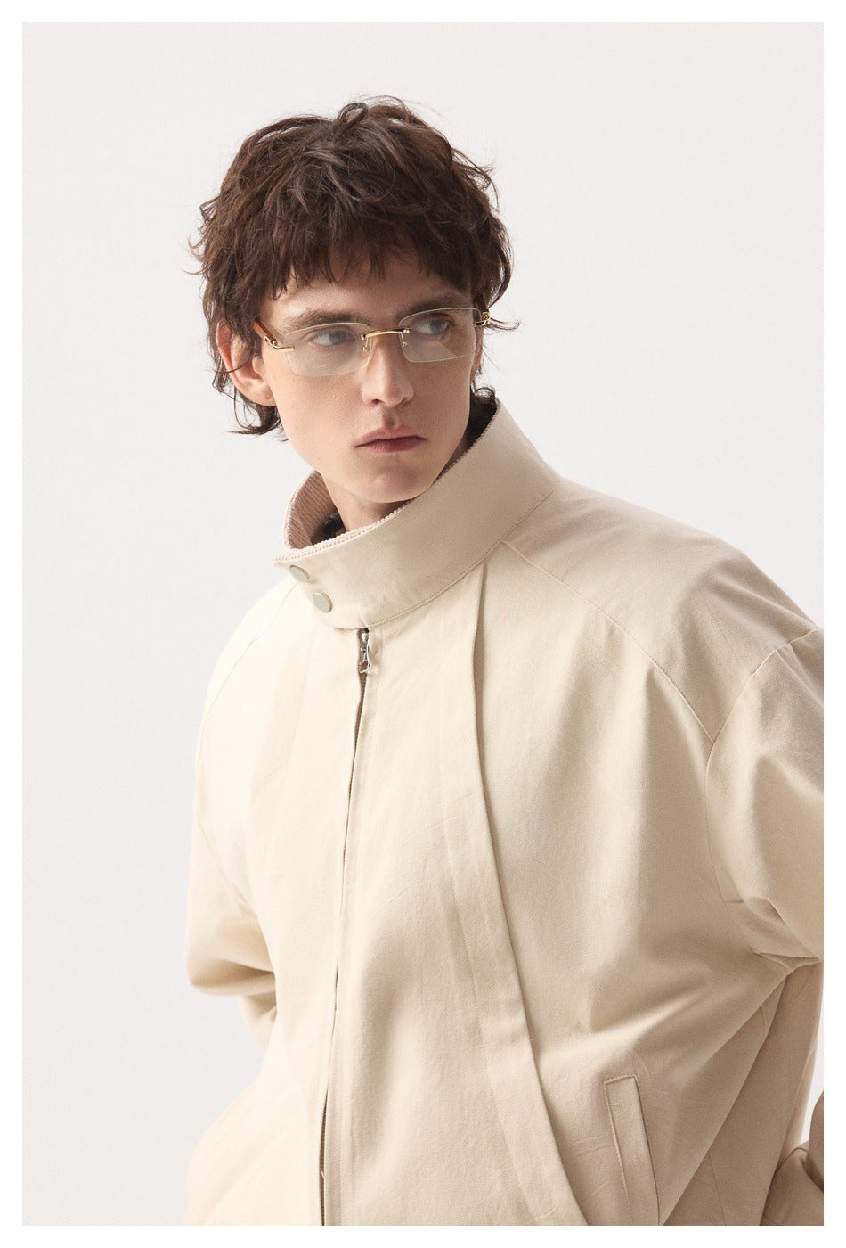 Model wearing a pale beige jacket with a high snap collar and front zip, shown from an angled front view.