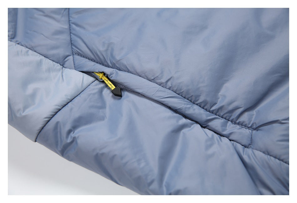Close-up of a small yellow zipper pull with a black tab on a seam of the slate-blue jacket.