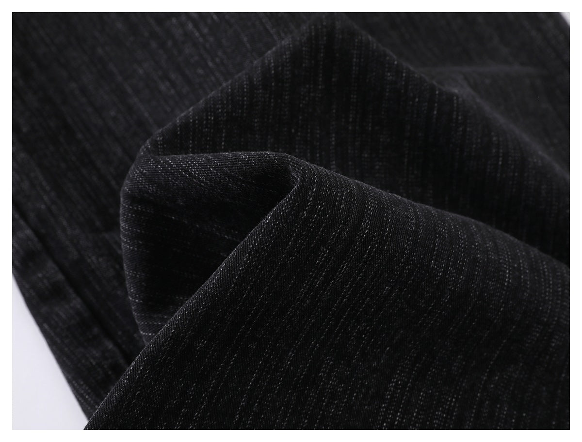 Macro view of folded black denim fabric with fine gray vertical texture.