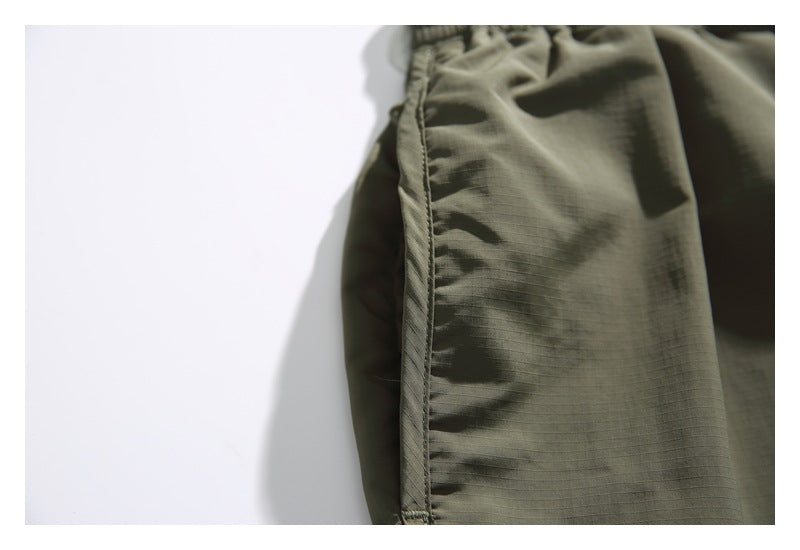 Close-up of the olive shorts' side seam and subtly gridded fabric texture.