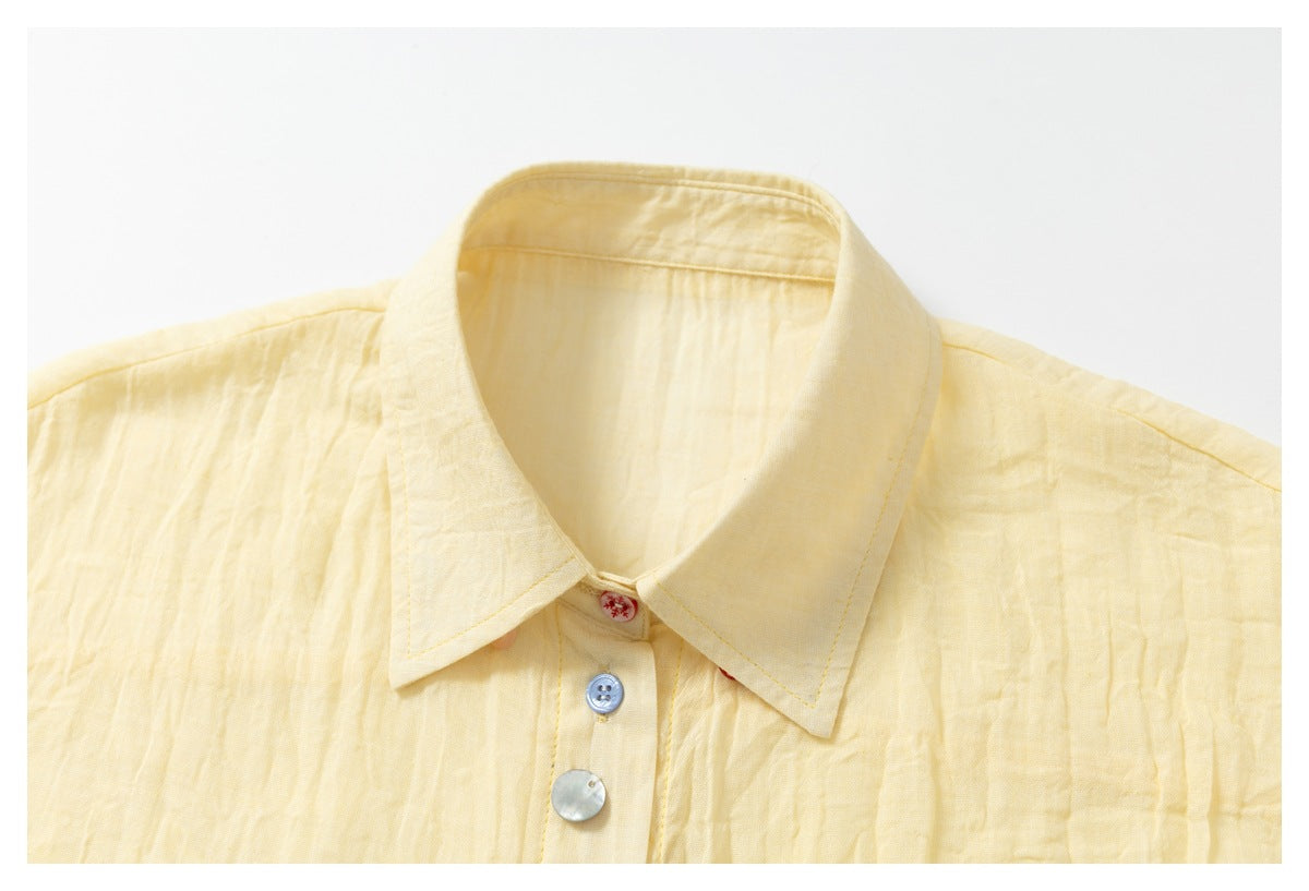 Close-up of the pale yellow shirt collar and upper placket with contrasting buttons.