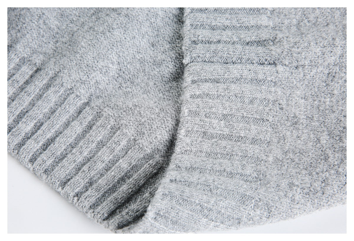 Close-up of light gray knit fabric showing ribbed trim and a folded seam.