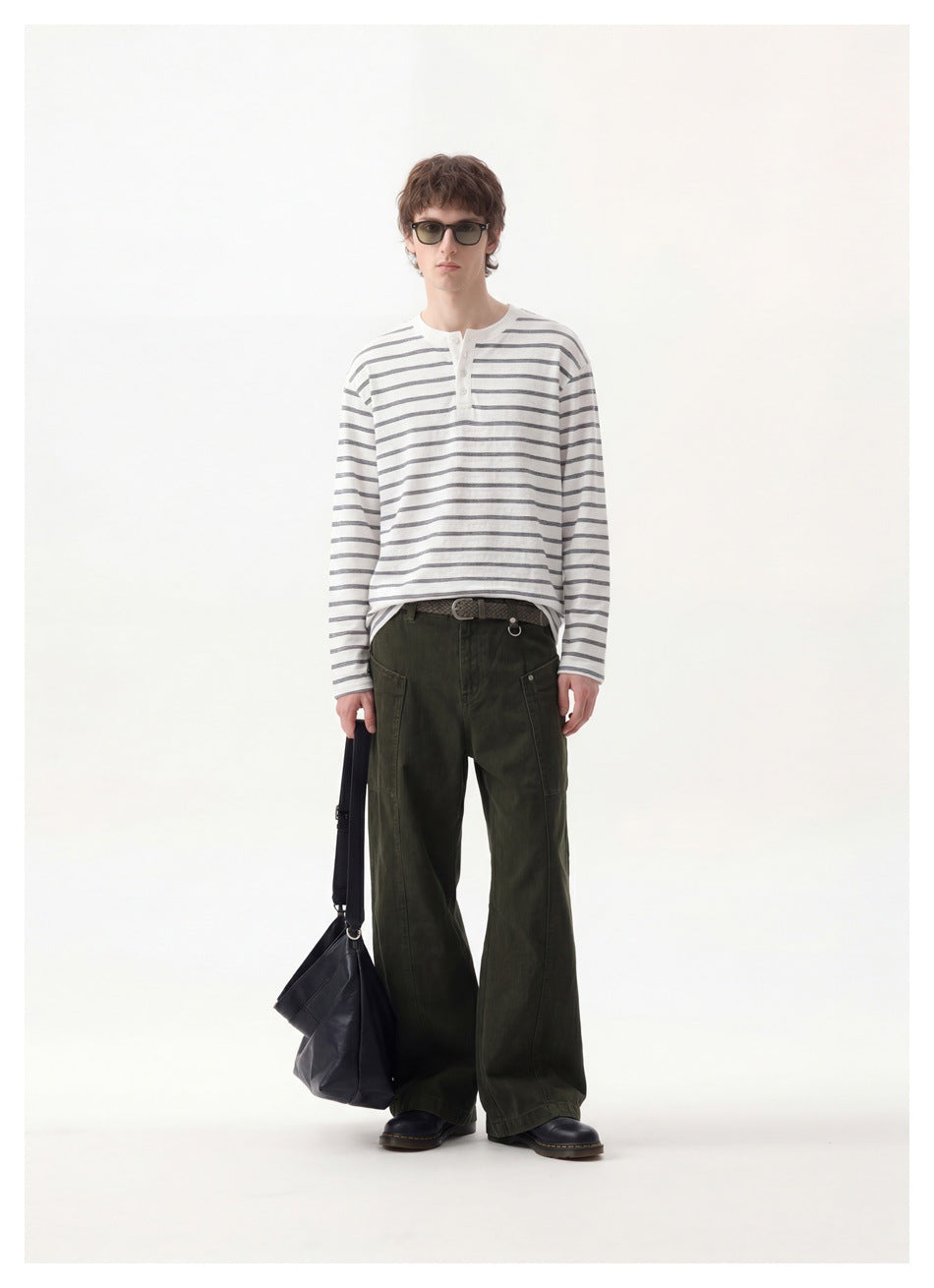 Model wearing a gray-striped white henley top with olive wide-leg pants, sunglasses and a black bag, full-length view