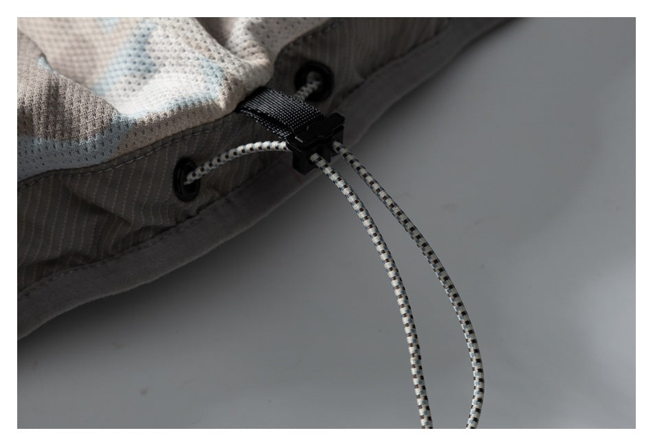 Close-up of the vest's adjustable hem drawcord, eyelets, and black cord lock.