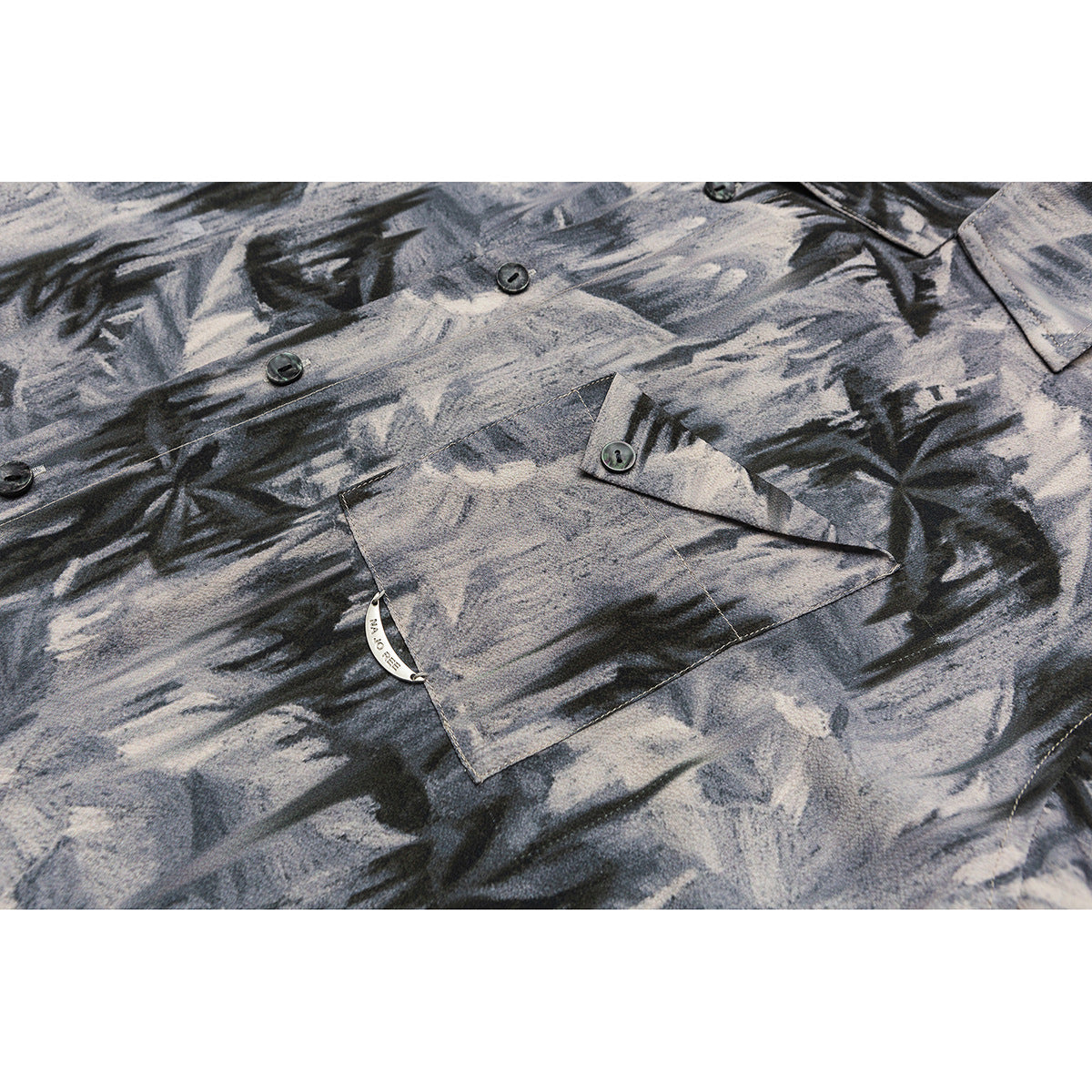 Close-up of an abstract gray and black shirt front with a buttoned flap chest pocket.