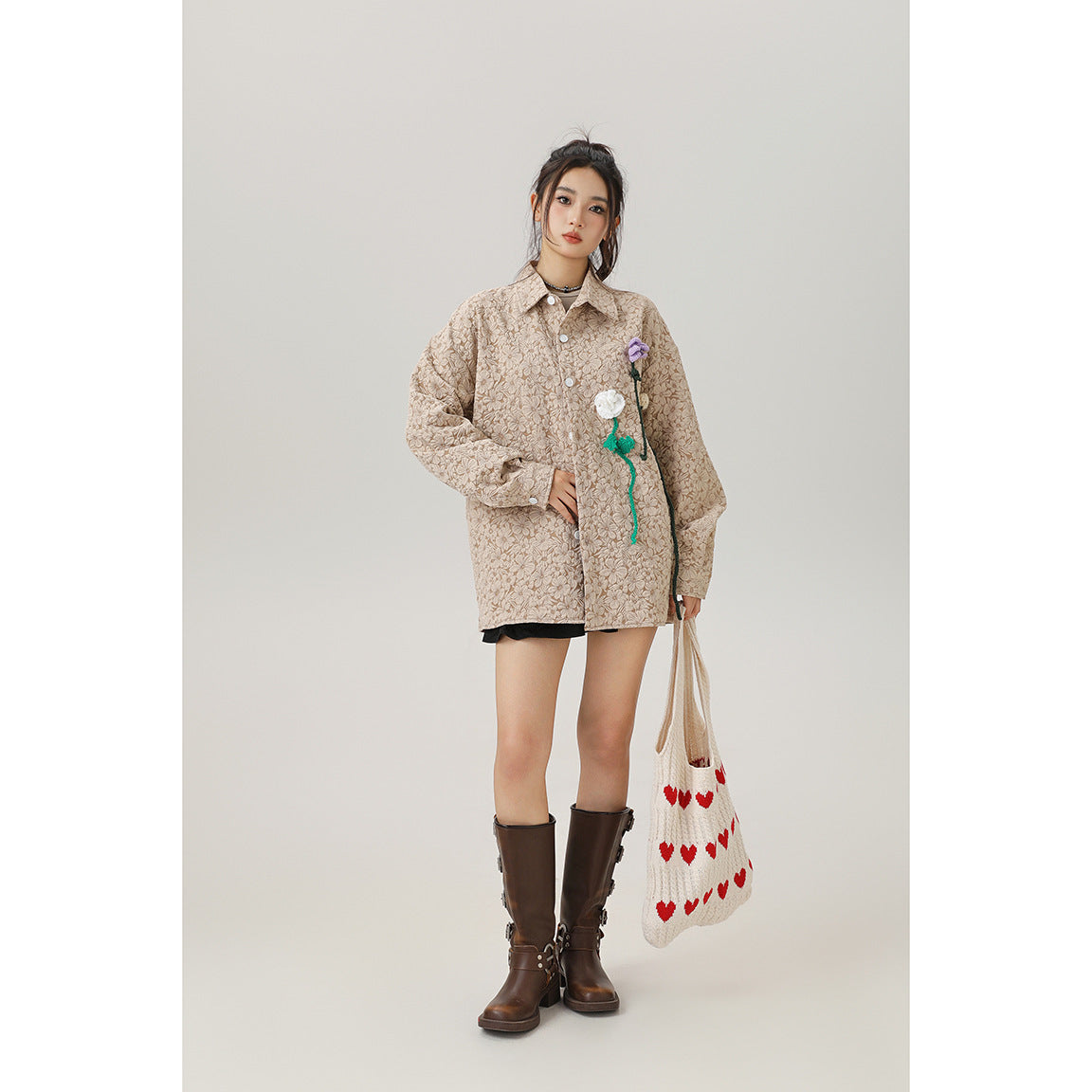 Model wearing an oversized beige floral jacket with colorful flower appliqués, black skirt, and brown boots.