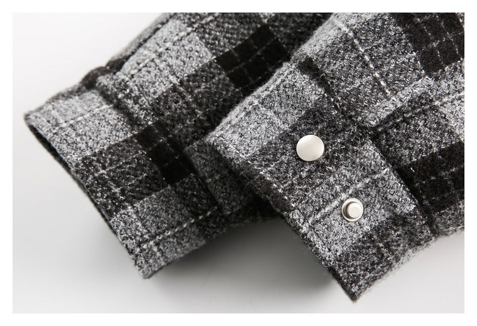 Close-up of a plaid garment cuff with a folded tab and silver snap fasteners.