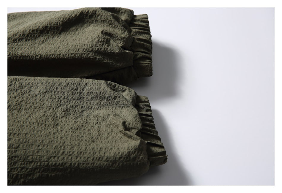 Close-up of two olive jacket sleeve cuffs with gathered elastic openings.