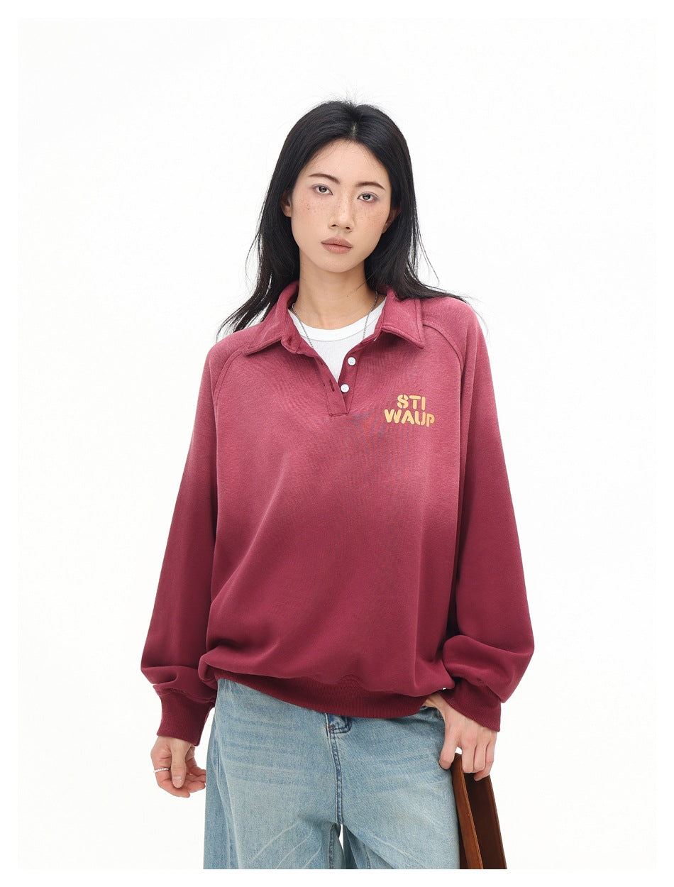 Woman wearing a red gradient polo-collar sweatshirt over a white tee with light-wash jeans, close three-quarter view