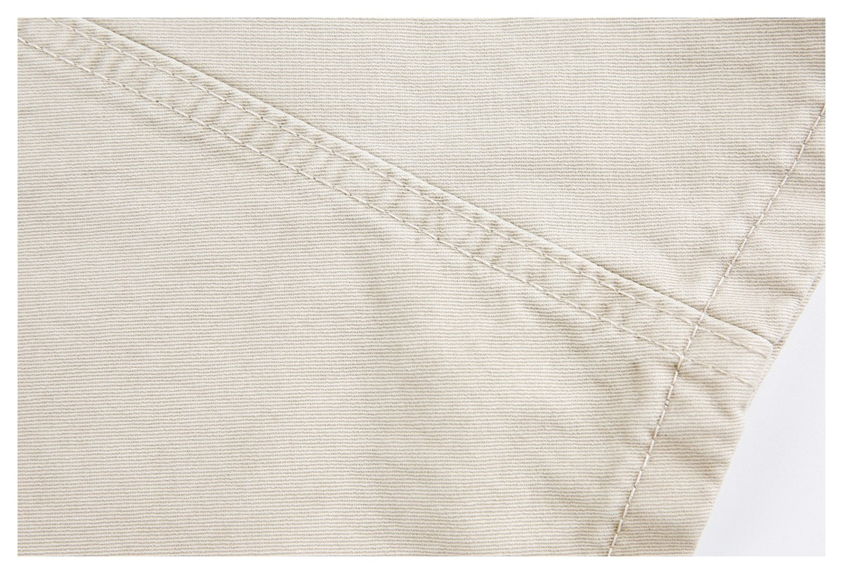 Close-up of light beige fabric with diagonal stitching and a reinforced seam.