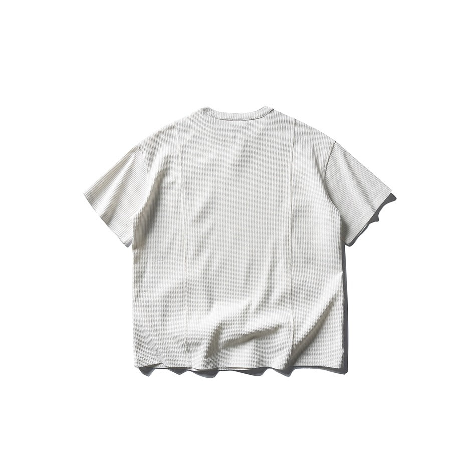 Back view of an off-white short-sleeve top with a textured surface and vertical seams.
