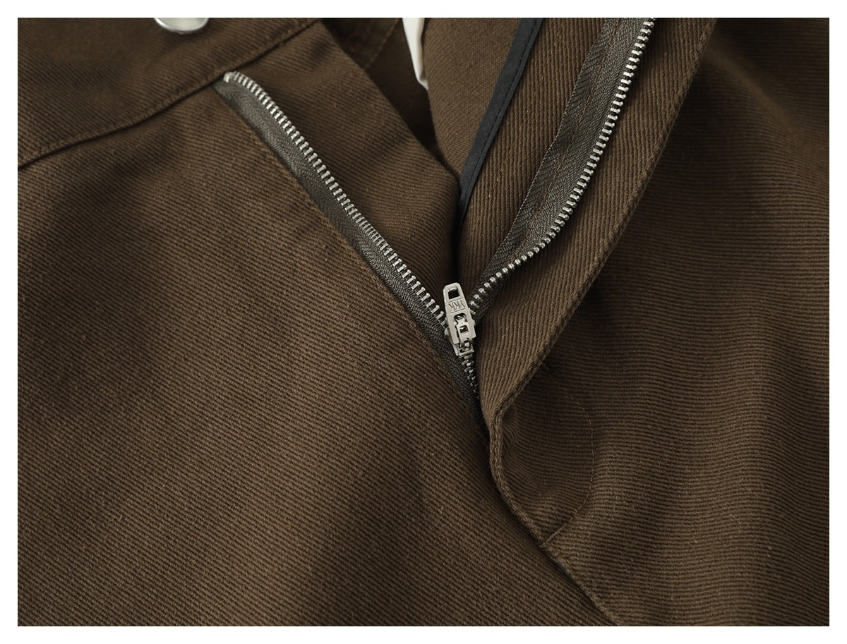 Close-up of brown trousers showing the front zipper fly and stitching.
