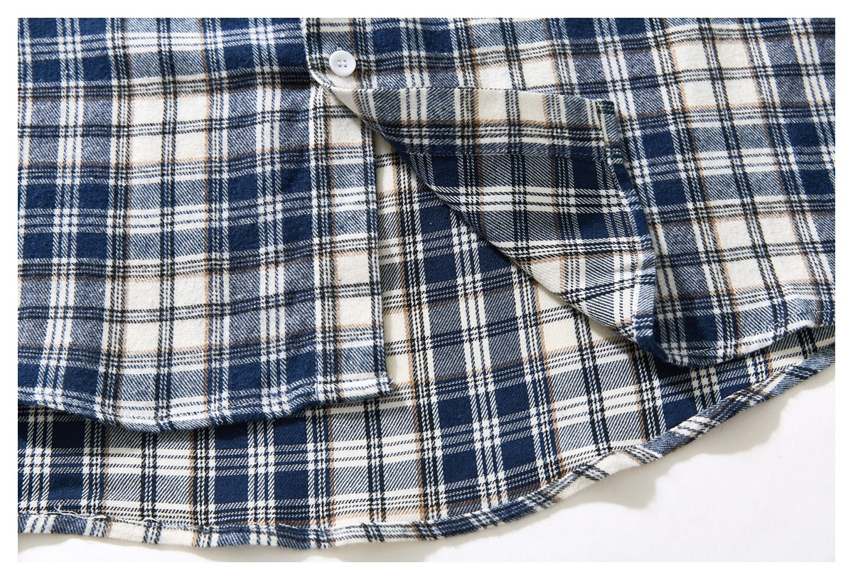 Close-up of the navy and cream plaid shirt's chest pocket, buttons, and curved lower hem.