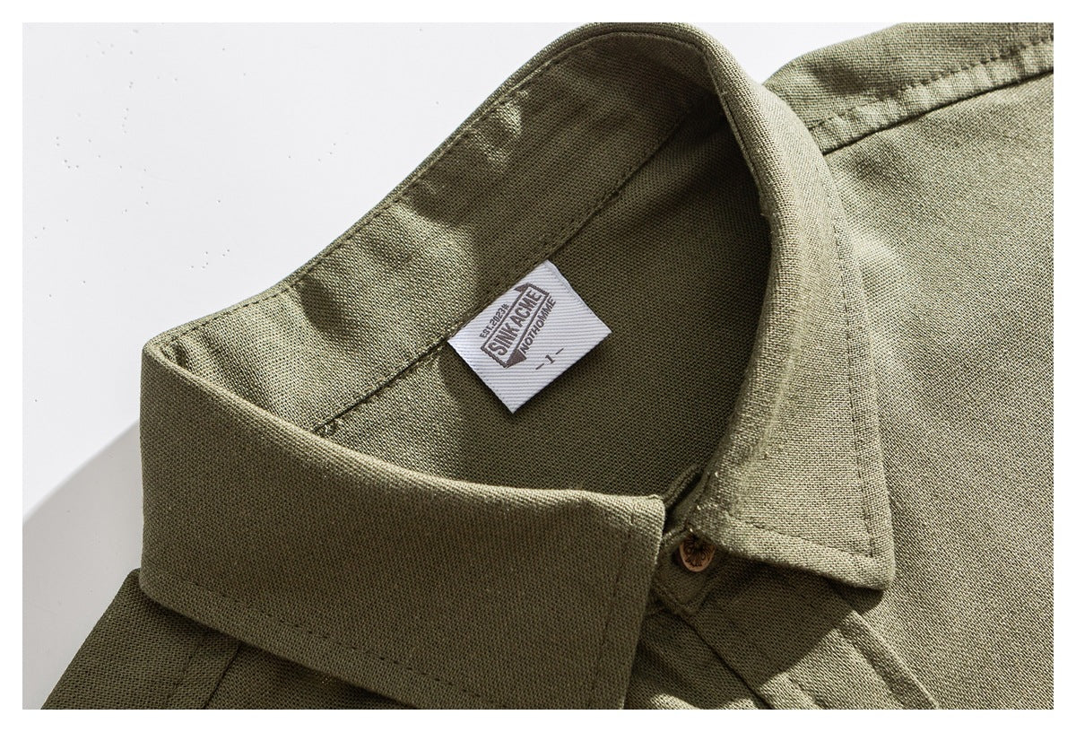 Close-up of the olive shirt's pointed collar, button, textured fabric, and sewn-in neck label.