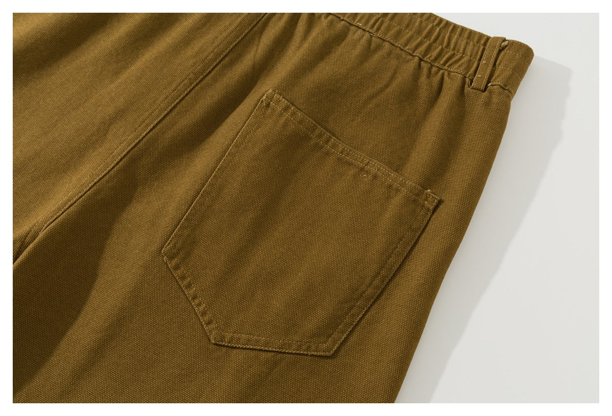 Close view of the back of mustard-brown shorts, showing a stitched patch pocket and waistband.
