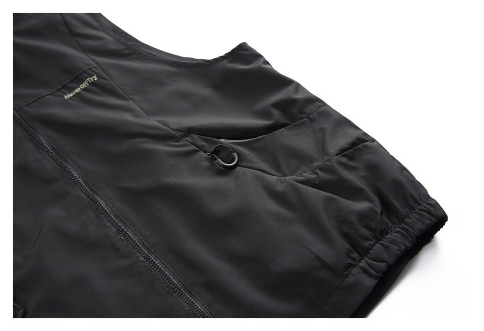 Close-up of the black vest's chest pocket with a ring pull, zipper and embroidered text.