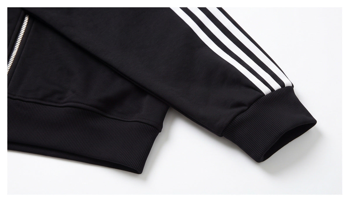 Close-up of a black jacket sleeve with three white stripes and a ribbed cuff and hem.