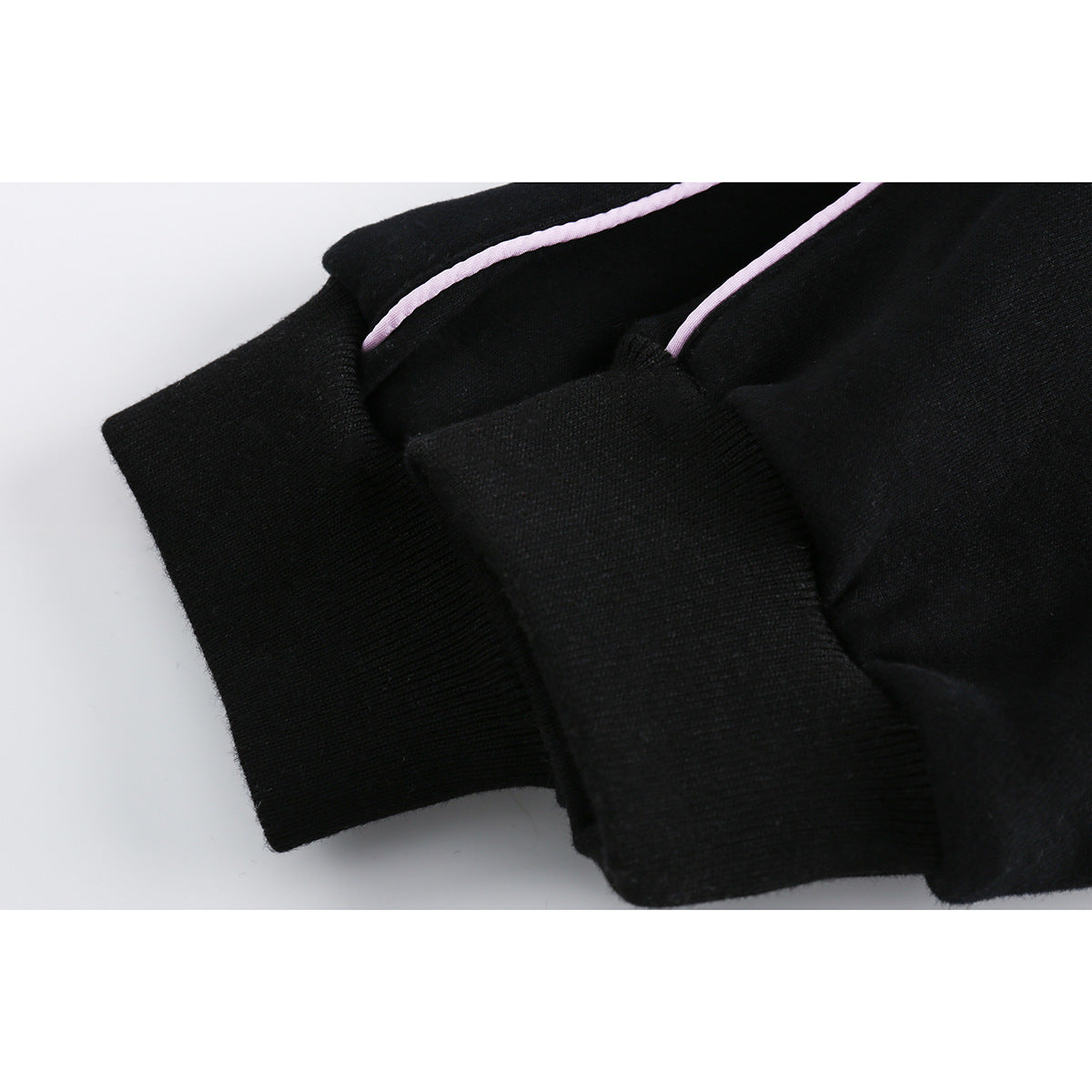 Close-up of a black hoodie cuff and sleeve with narrow lavender piping.