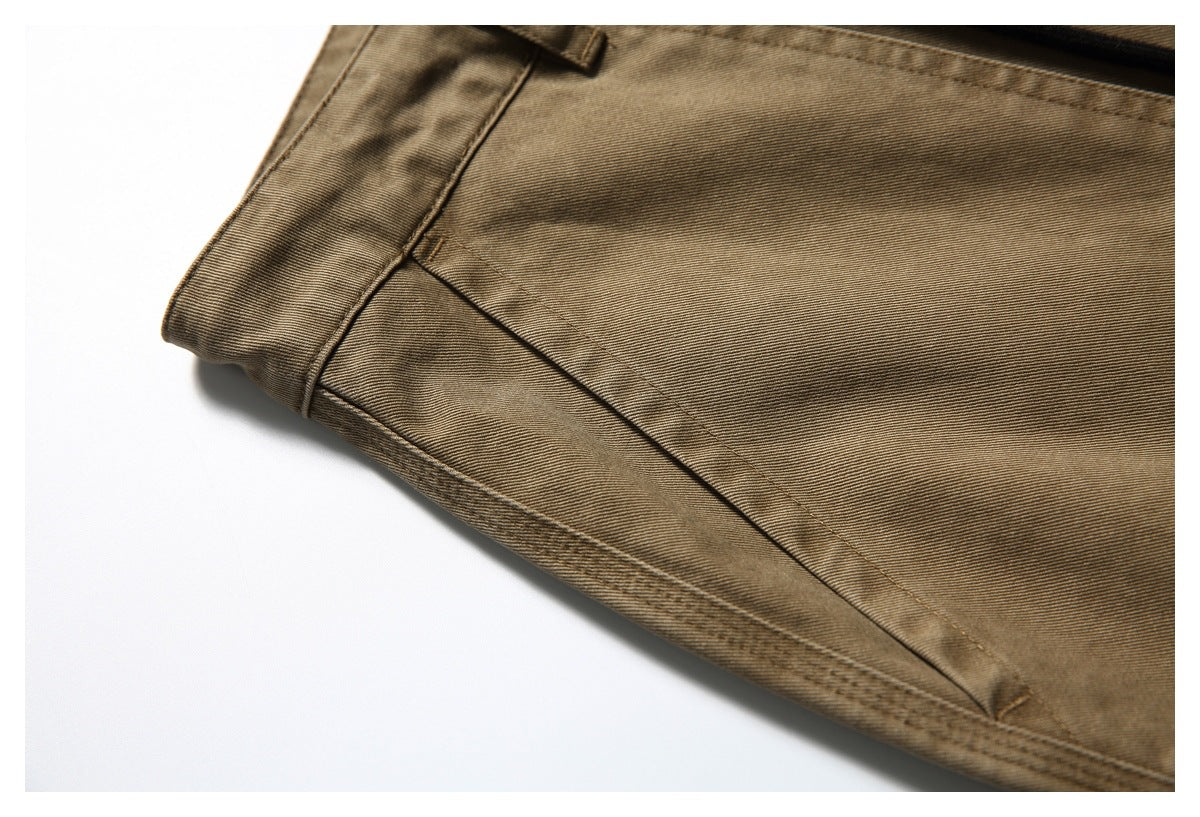 Close-up of tan-brown trouser fabric showing a slanted seam and stitched pocket edge.
