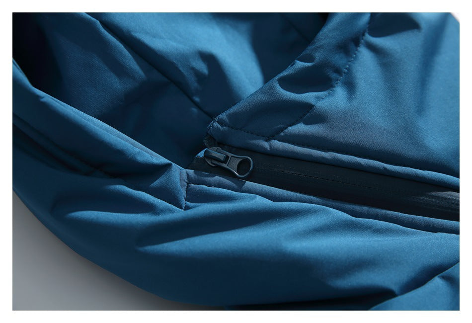 Close-up of a teal-blue jacket hood seam and black zipper pull.