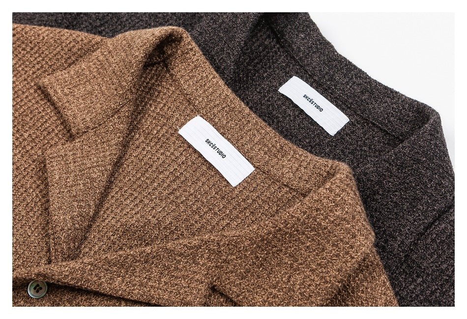 Close-up of brown and charcoal knit cardigans showing shawl collars, buttons, and sewn neck labels.