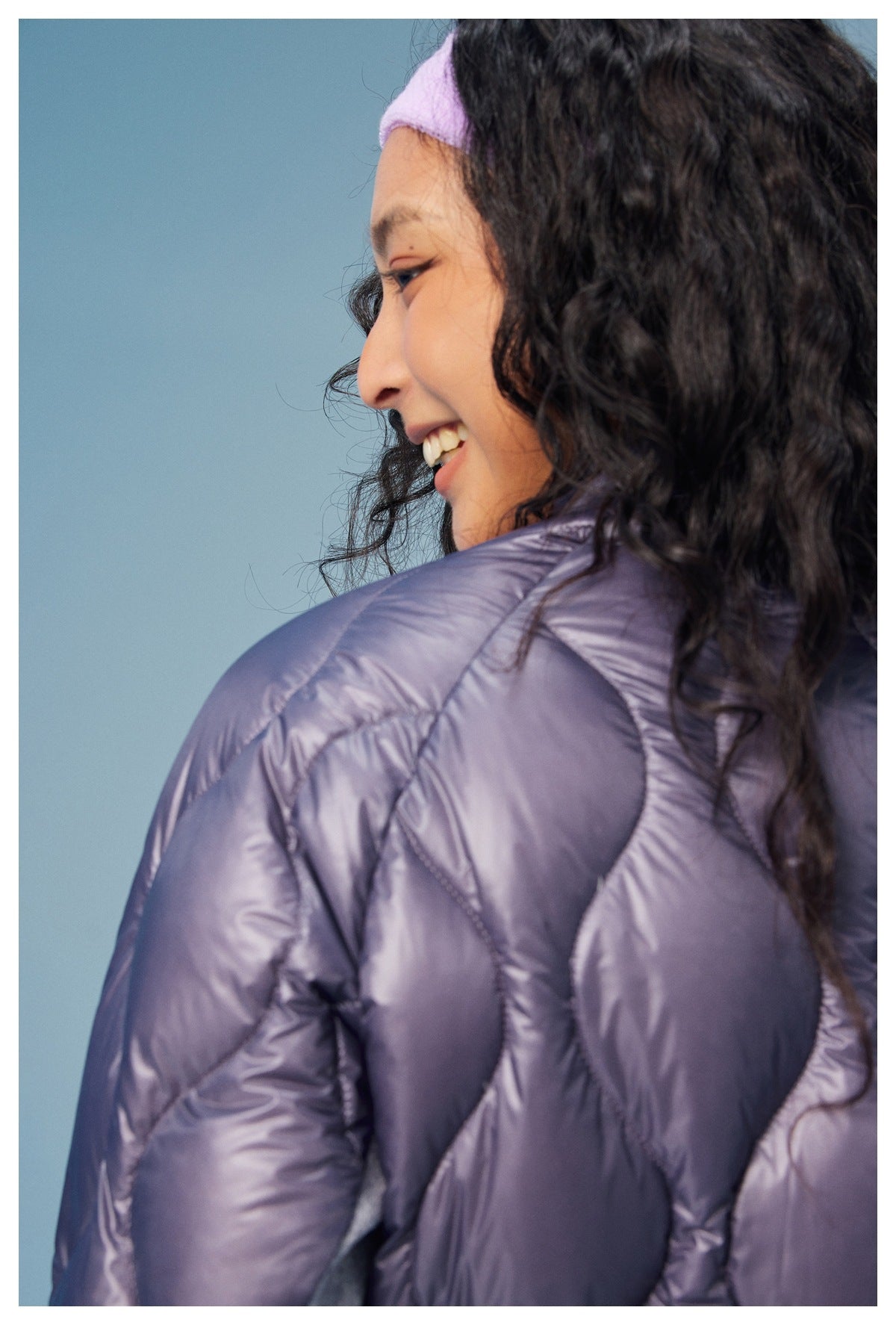 Close-up of the purple jacket's quilted shoulder and sleeve, with the model's profile visible.