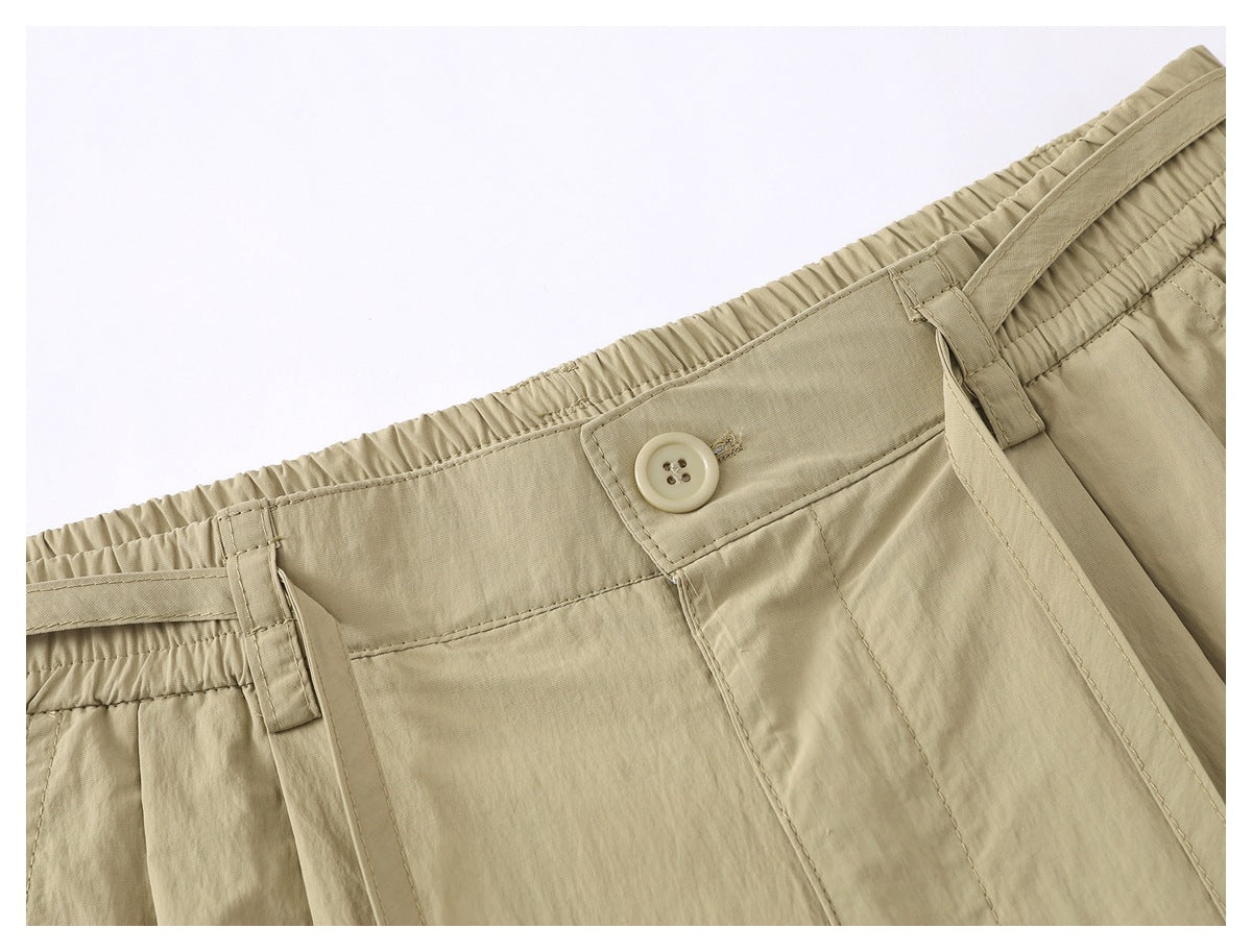 Close-up of beige shorts showing the waistband, button, belt loops and front closure stitching.