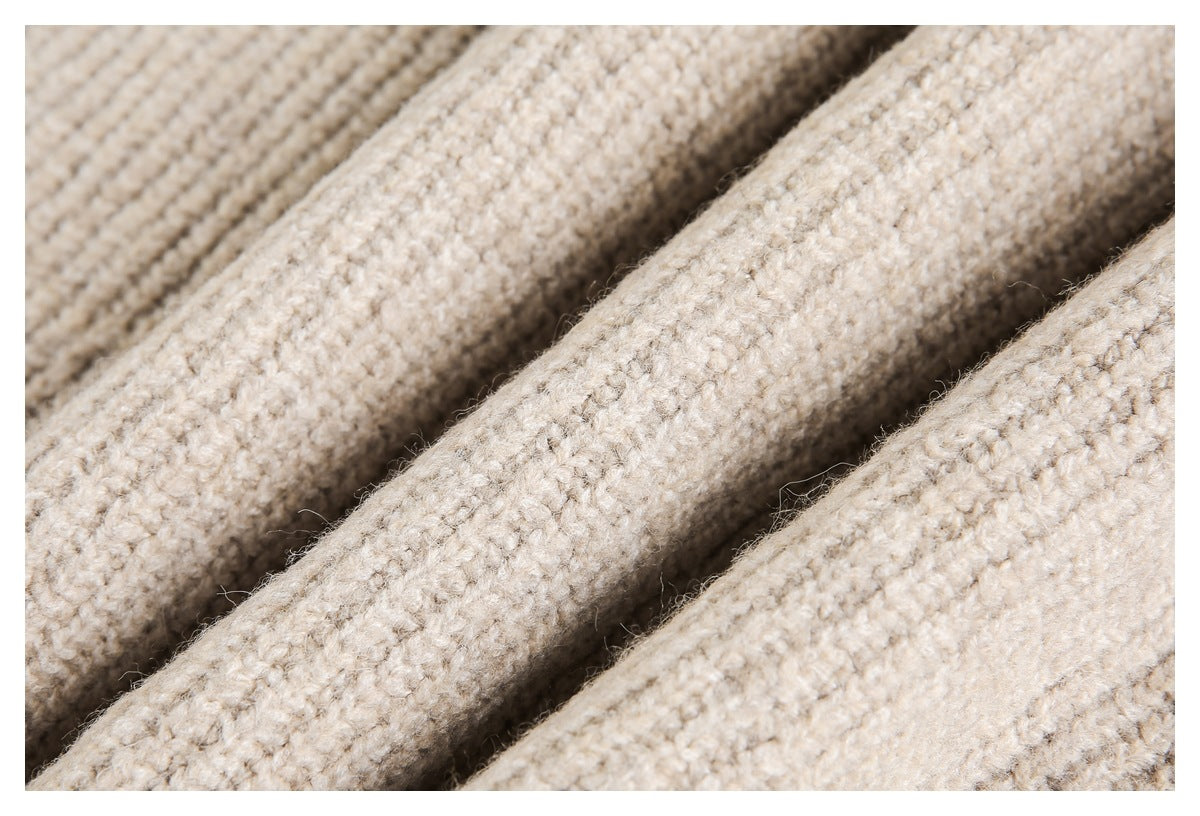 Close-up of chunky cream-beige knitted fabric with a visible looped texture.