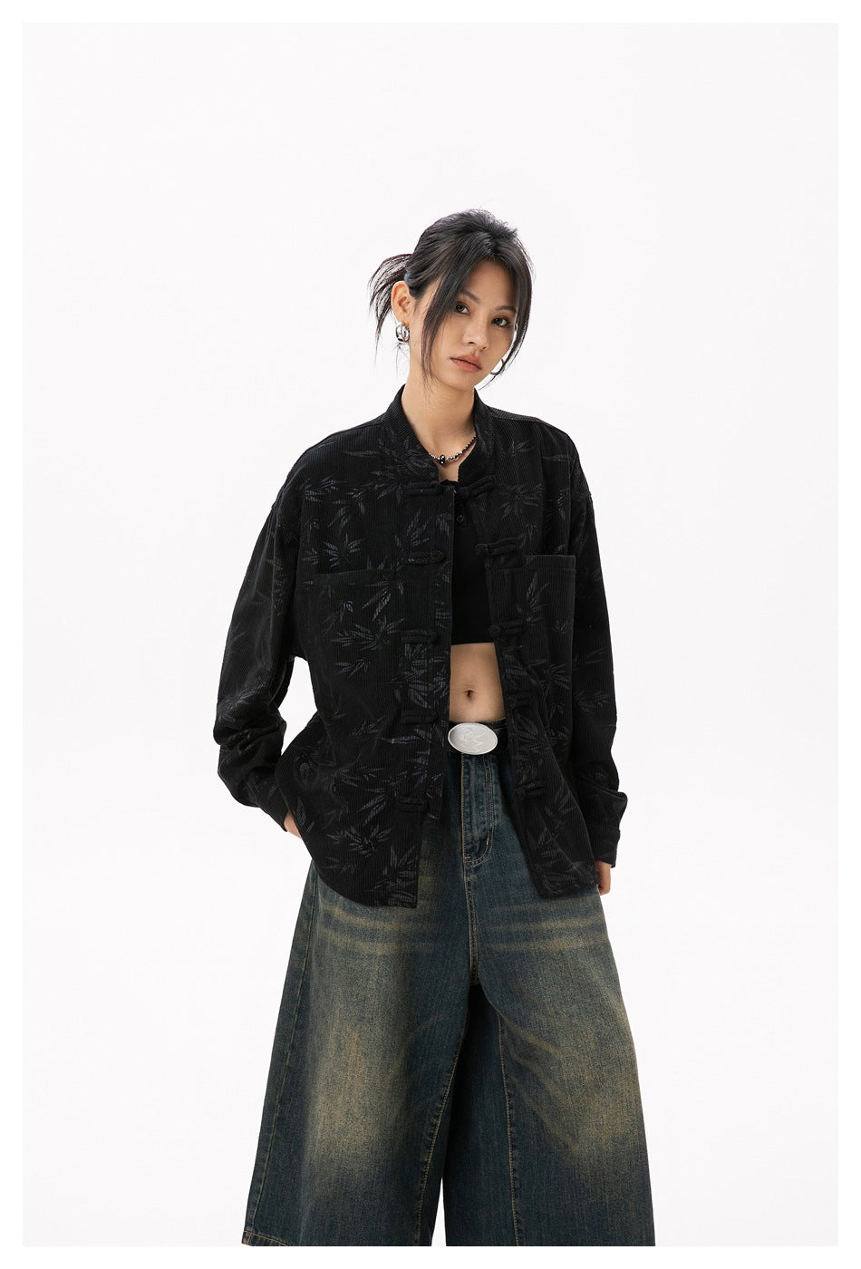 Woman wearing black bamboo-pattern frog-knot shirt open over a black crop top with wide-leg jeans